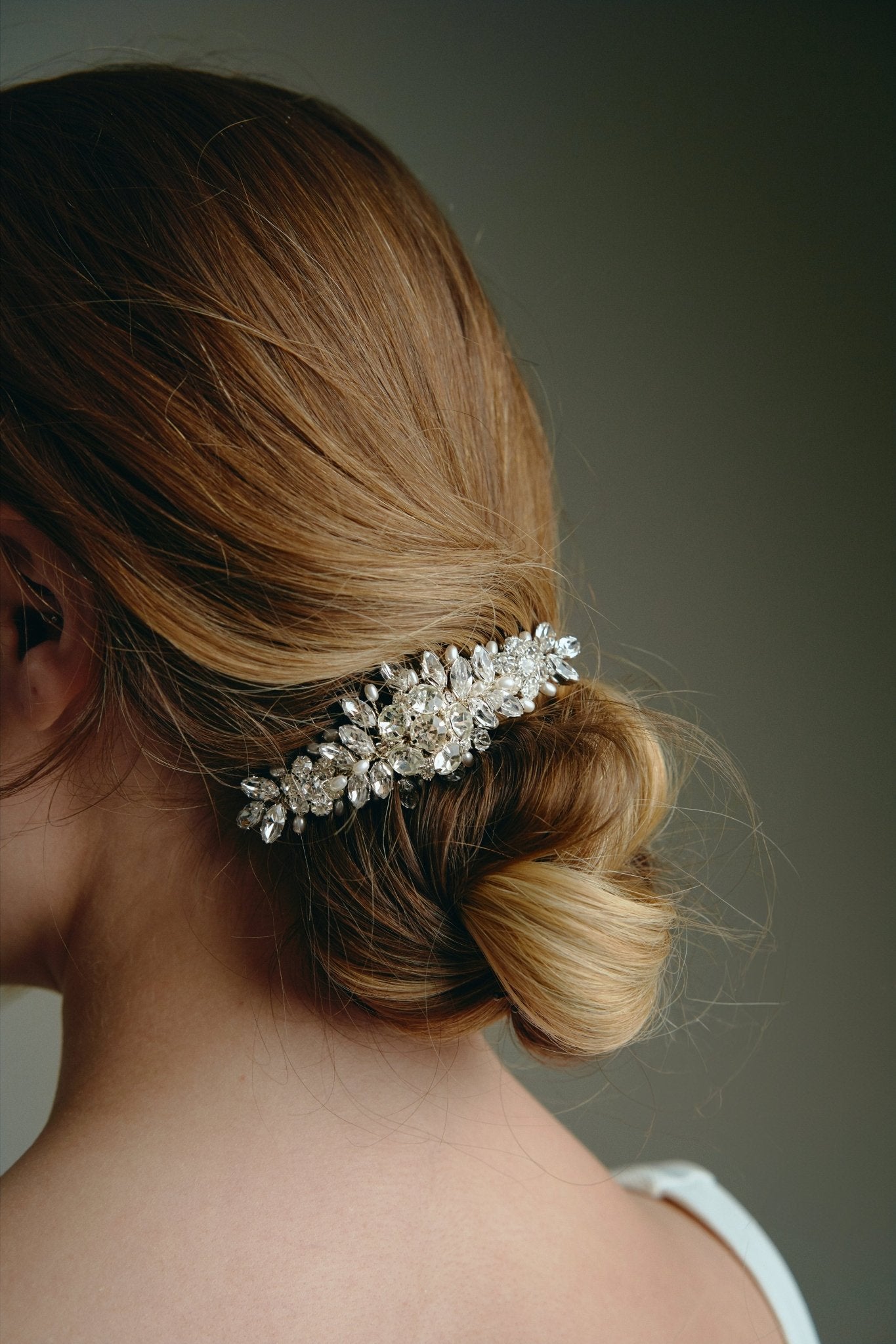 Bridal hair comb with silver crystals and freshwater pearls worn by a bride with a low bun updo