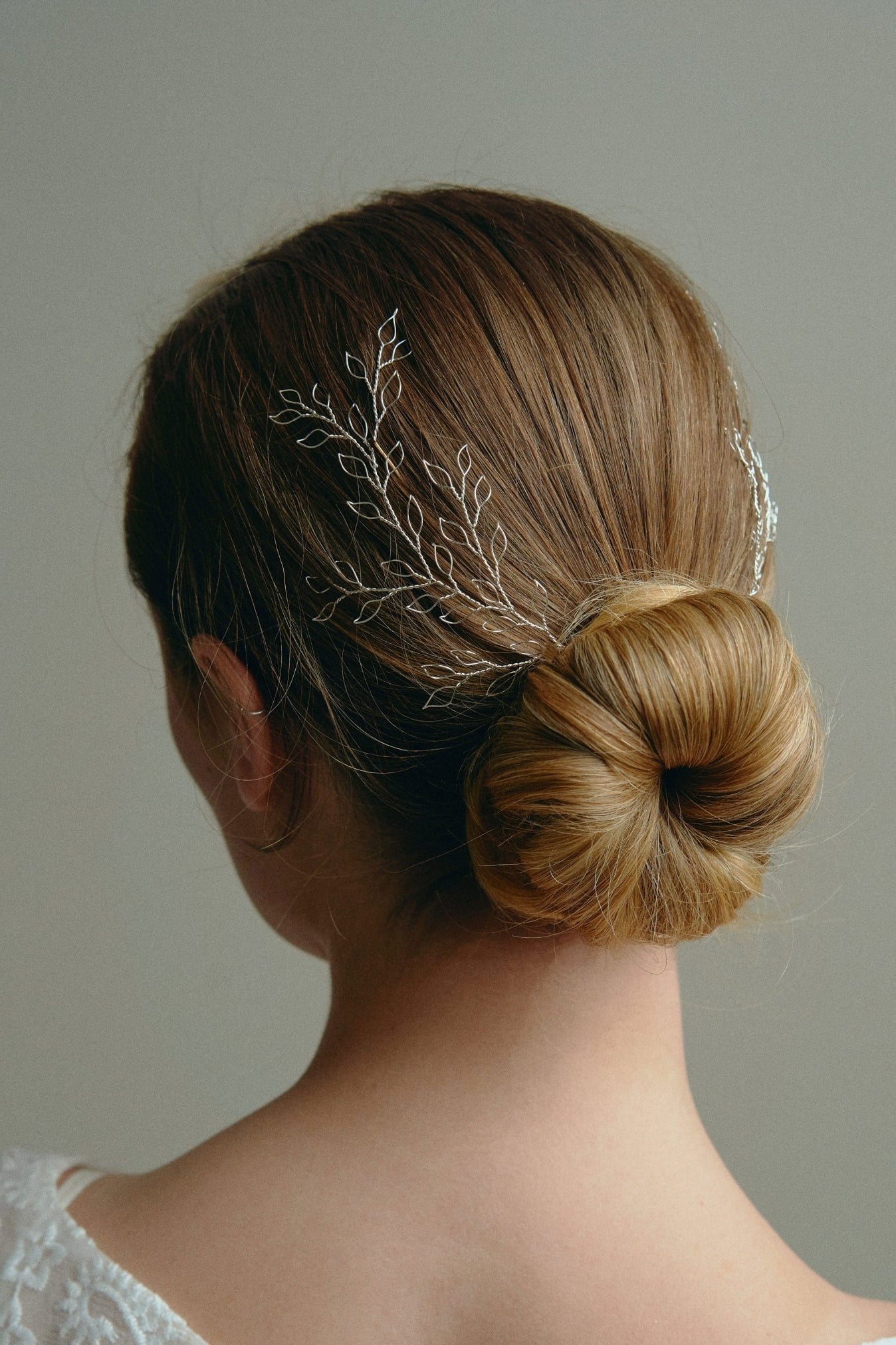 Wedding hair vine - model wears a pair of silver leafy delicate hair vines in the back of a low bun 