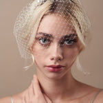 Short birdcage veil styled with pearl and star hairpin