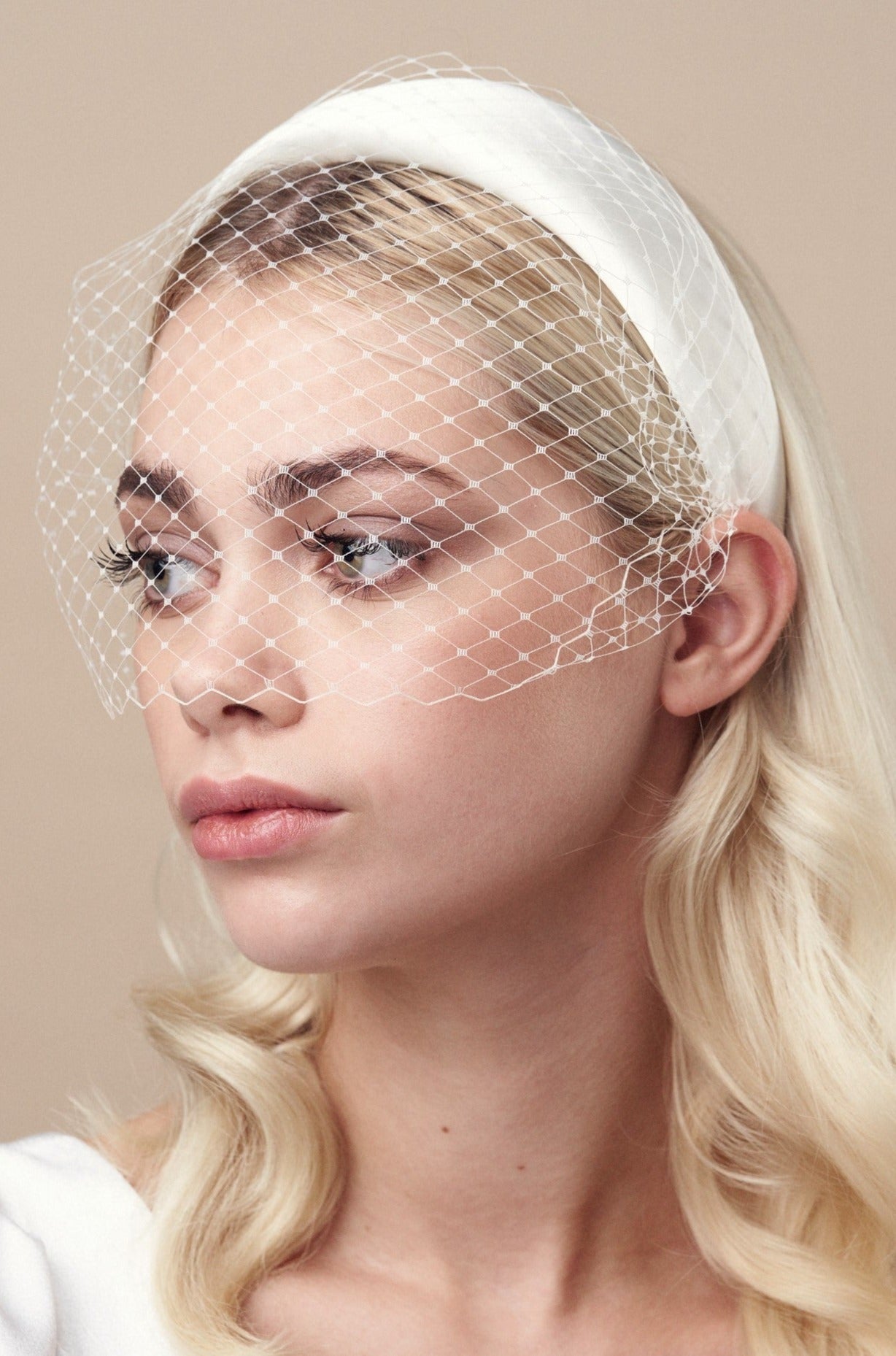 Ivory padded headband with adjustable birdcage veil attached worn above the mouth