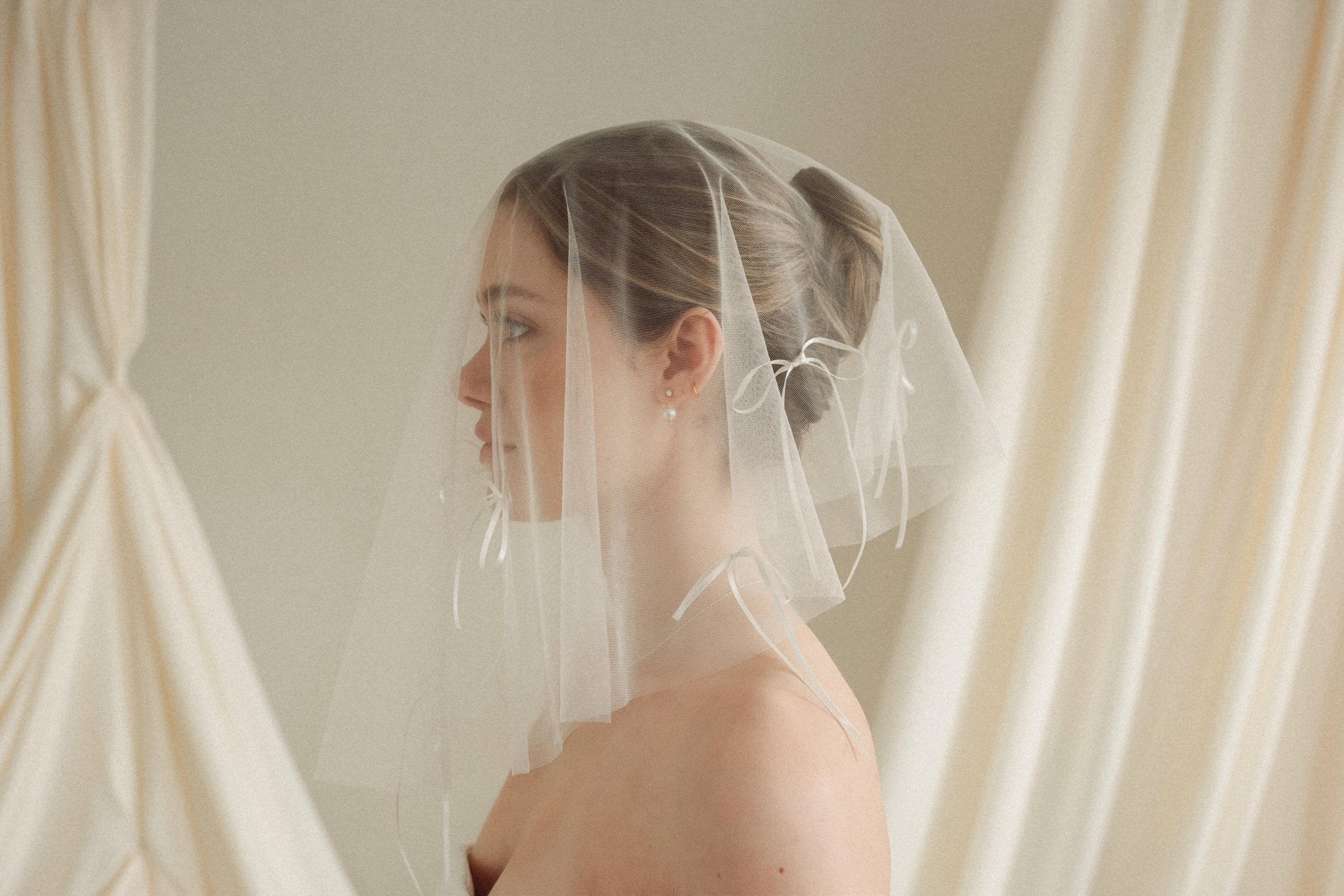 bride wears a drop micro veil with bow details 