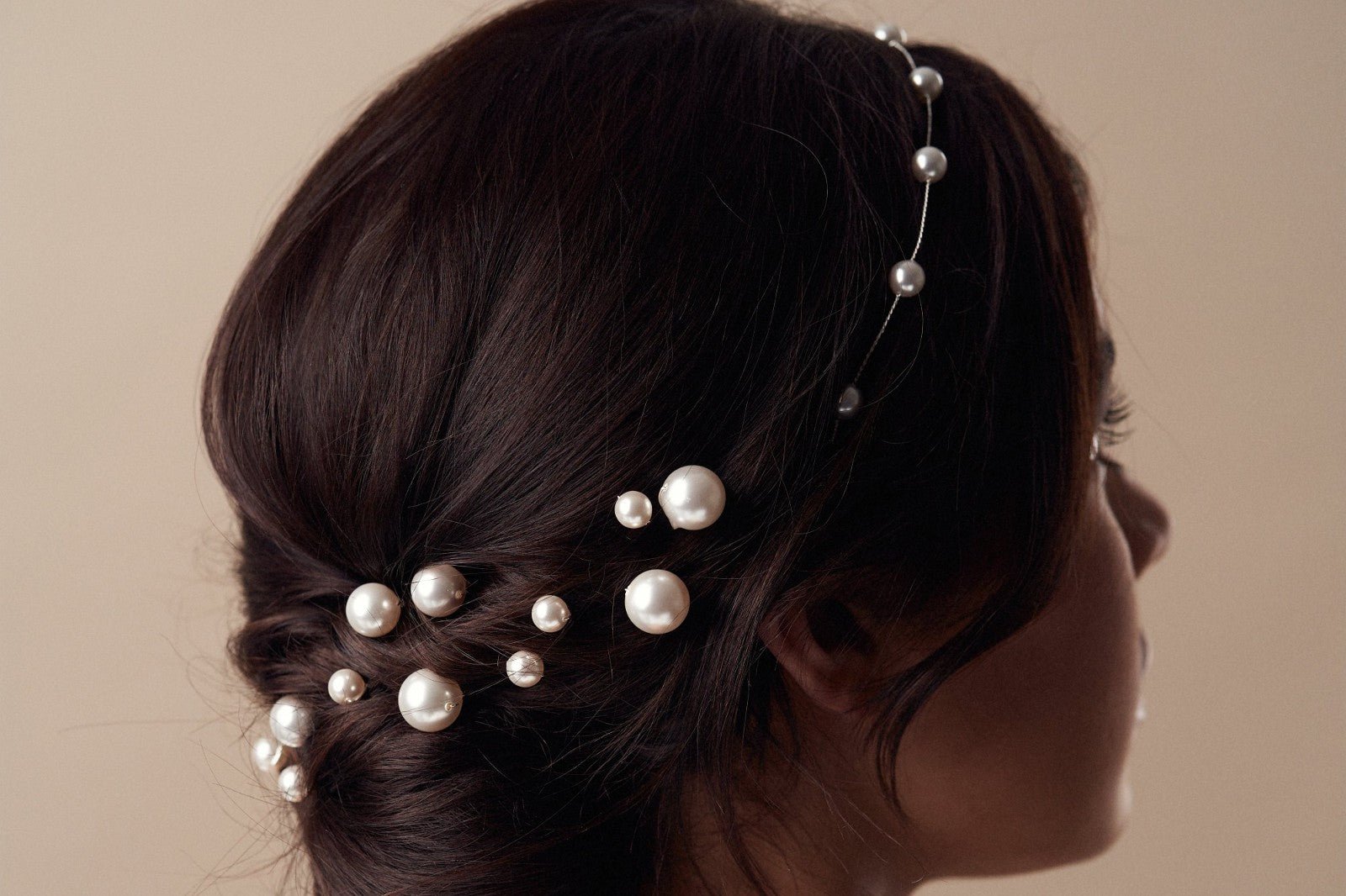 model with dark hair in a low bun wearings scattered pearl hairpins with matching pearl headband