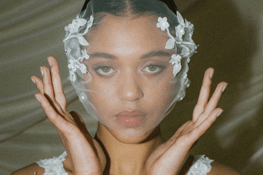 Close-up of a modern bride wearing a micro veil in the UK, featuring a tulle short veil style with floral embellishment, styled for a contemporary editorial wedding look.