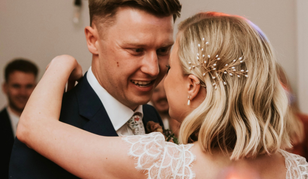 blonde bride wears gold and pearl botanical hairpins with a short bob as she embraces her new husband