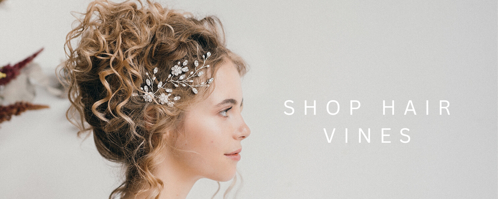 bride wears delicate simple floral hairvine above the ear with loose curled updo