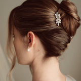 Bride wears pearl and crystal stud drop earrings with a small silver crystal comb with elegant chignon updo 