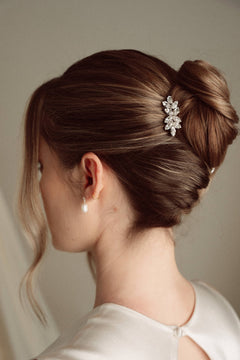 Bride wears pearl and crystal stud drop earrings with a small silver crystal comb with elegant chignon updo 