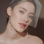bride wears a sheer tulle birdcage style veil with long drop pearl earrings and a baroque coin pearl necklace