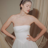bride wears a sheer tulle birdcage style veil with long drop pearl earrings and a baroque coin pearl necklace