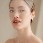 bride wears a sheer tulle birdcage style veil with small crystal and pearl stud drop earrings and a baroque coin pearl necklace