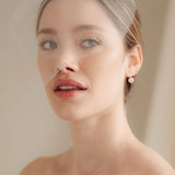 bride wears a sheer tulle birdcage style veil with small crystal and pearl stud drop earrings and a baroque coin pearl necklace