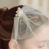 Bride wears pearl cluster hair pins and crystal and perl delicate drop stud earrings  with simple tulle birdcage veil