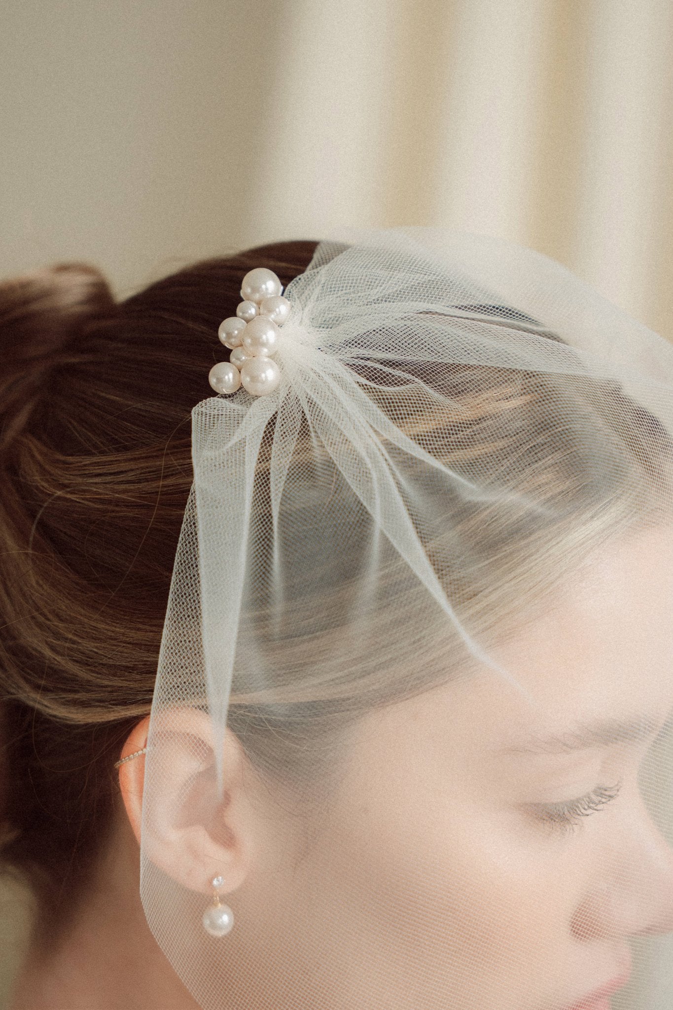 Bride wears pearl cluster hair pins and crystal and perl delicate drop stud earrings  with simple tulle birdcage veil