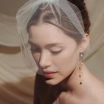 Close-up of a woman wearing a long delicate earring with four dangling pearl.