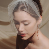 Close-up of a woman wearing a long delicate earring with four dangling pearl.