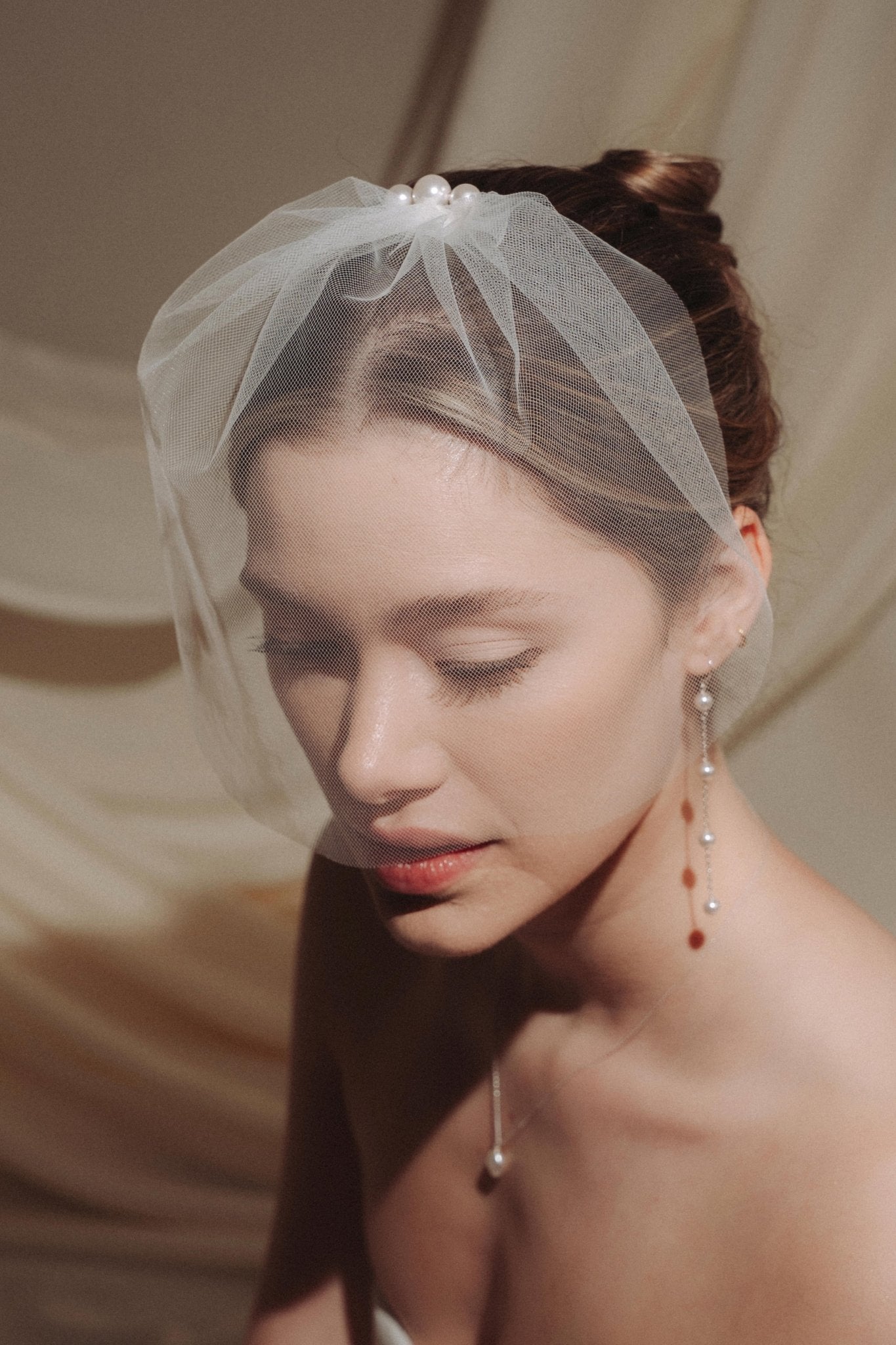 Close-up of a woman wearing a long delicate earring with four dangling pearl.