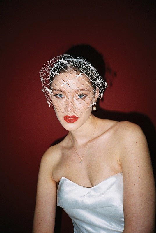 bride wears a bow birdcage veil on a slim headband