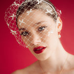 bride wears a bow birdcage veil on a slim headband
