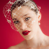 bride wears a bow birdcage veil on a slim headband