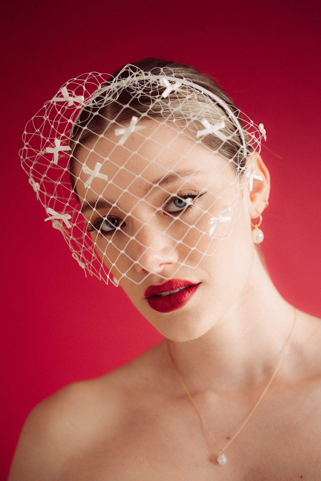 bride wears a bow birdcage veil on a slim headband