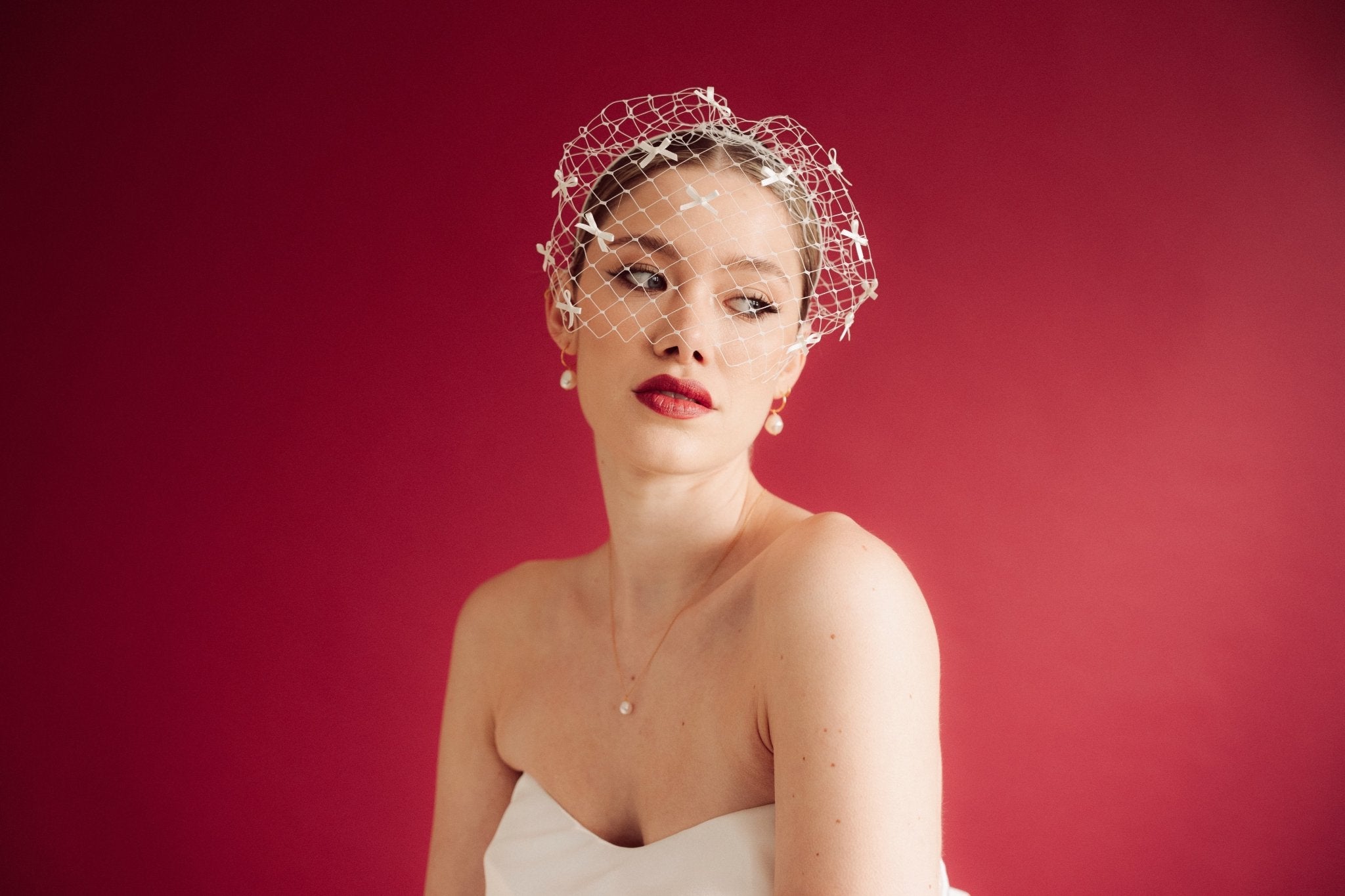 bride wears a bow birdcage veil on a slim headband