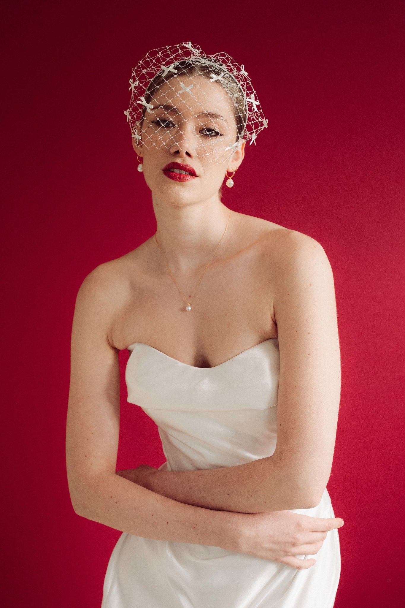 bride wears a bow birdcage veil on a slim headband