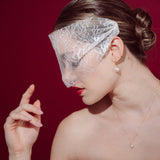 bride wears a sheer chantilly lace mask micro veil with gold hoop vegan baroque pearl earrings