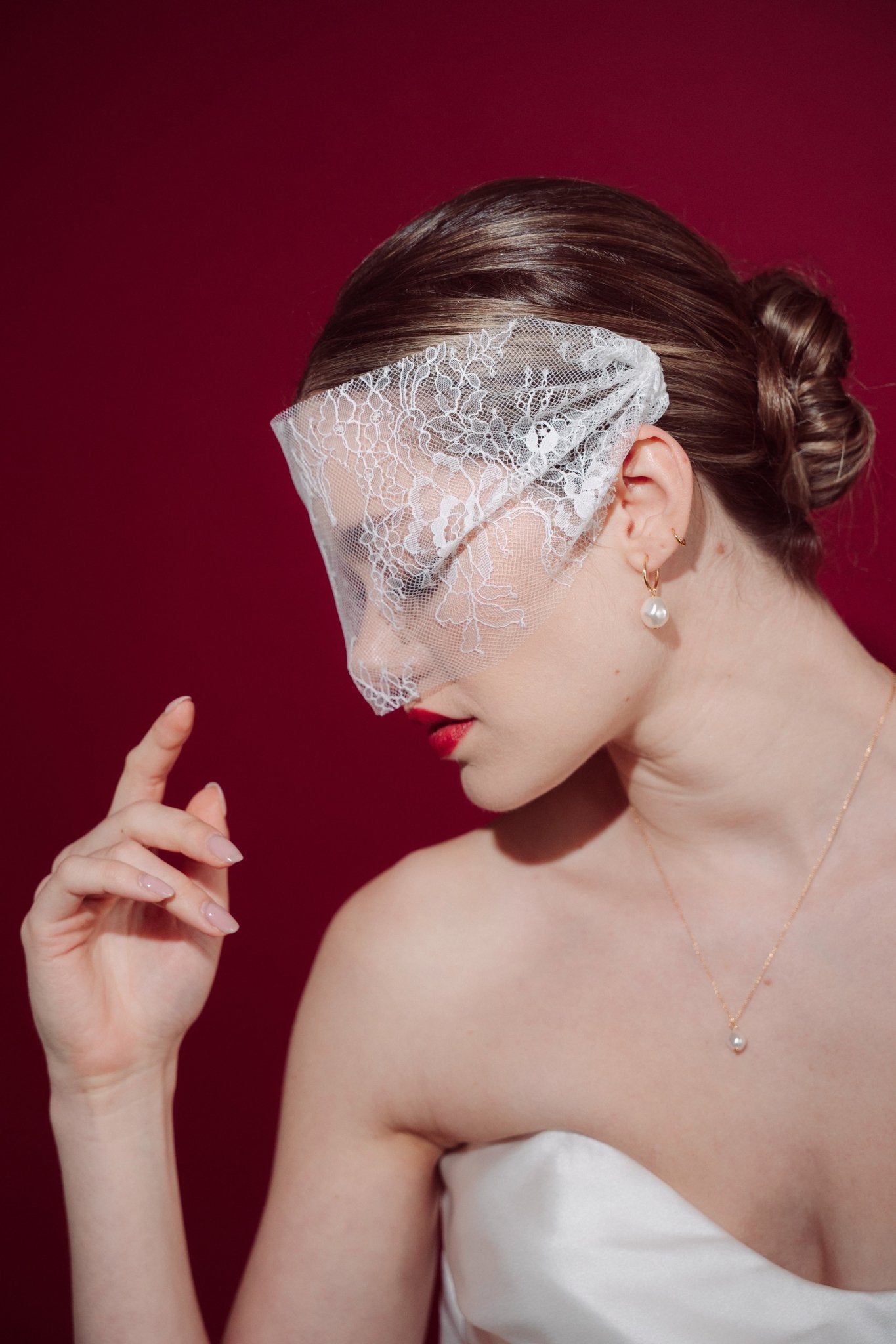 bride wears a sheer chantilly lace mask micro veil with gold hoop vegan baroque pearl earrings