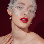 Bride wearing a lace veil and gold hoop earrings with a single vegan baroque pearl