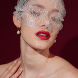Bride wearing a lace veil and gold hoop earrings with a single vegan baroque pearl