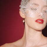 bride wears a sheer chantilly lace mask micro veil with gold hoop vegan baroque pearl earrings  and matching necklace
