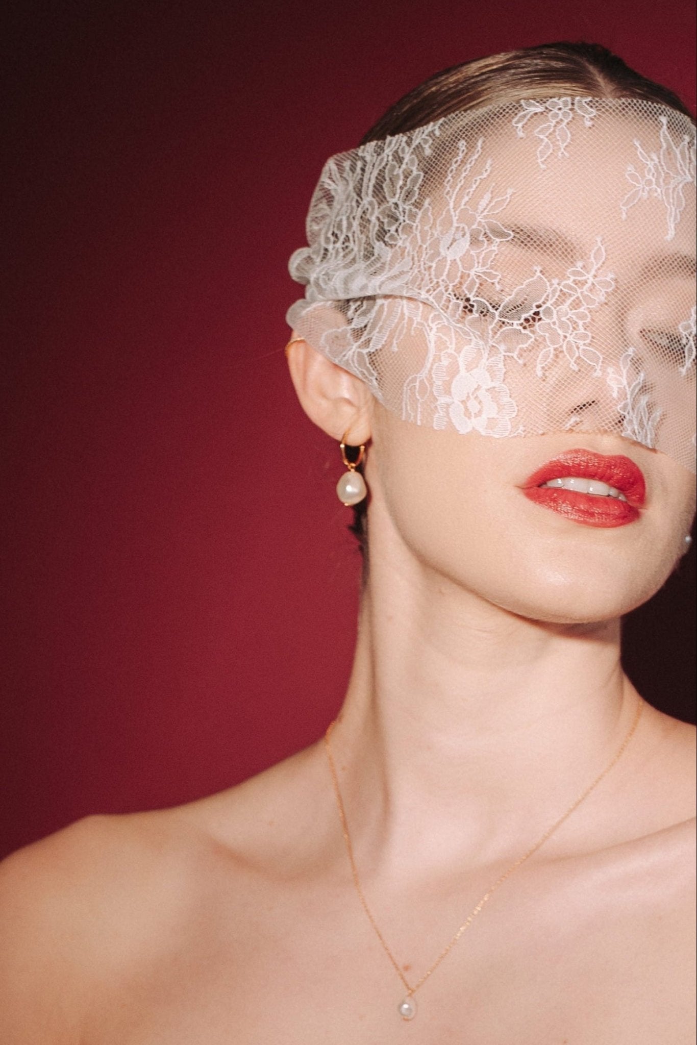 bride wears a sheer chantilly lace mask micro veil with gold hoop vegan baroque pearl earrings  and matching necklace