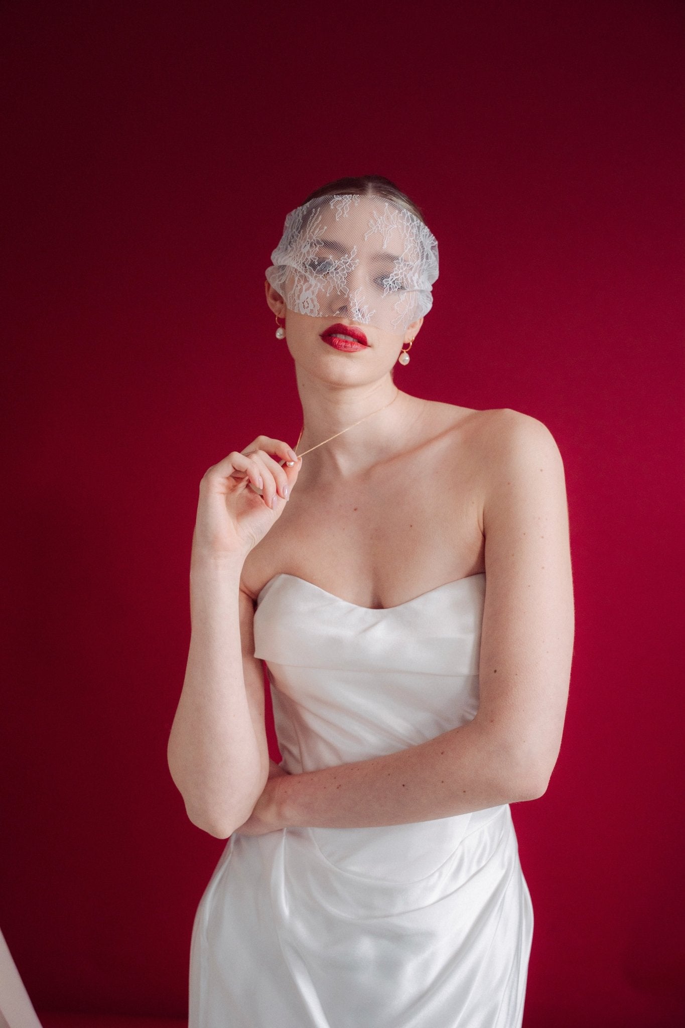 bride wears a sheer chantilly lace mask micro veil with gold hoop vegan baroque pearl earrings
