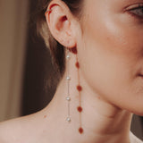 Close-up of a woman wearing a long delicate earring with four dangling pearl.
