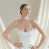 Bride wearing a white wedding dress with a chenille dot Merry Widow wedding veil against an ivory draped background