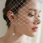 Bride wearing a chenille dot Merry Widow wedding veil and gold long crystal & baroque pearl drop earrings