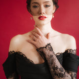 bride wears a gold baroque coin vegan pearl necklace, gold crystal drop earrings and a black tulle mask veil micro veil with a black lace dress