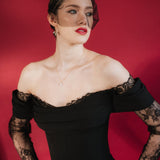 bride wears a gold baroque coin vegan pearl necklace, gold crystal drop earrings and a black tulle mask veil micro veil with a black off the shoulder gown 