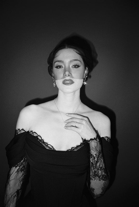 Black and white portrait of a bride wearing a gold baroque coin vegan pearl necklace, gold crystal drop earrings and a black tulle mask veil micro veil with a black lace dress