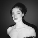 Black and white portrait of a bride wearing a gold baroque coin vegan pearl necklace, gold crystal drop earrings and a black tulle mask veil micro veil with a black lace dress