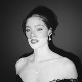 Black and white portrait of a bride wearing a gold baroque coin vegan pearl necklace, gold crystal drop earrings and a black tulle mask veil micro veil with a black lace dress