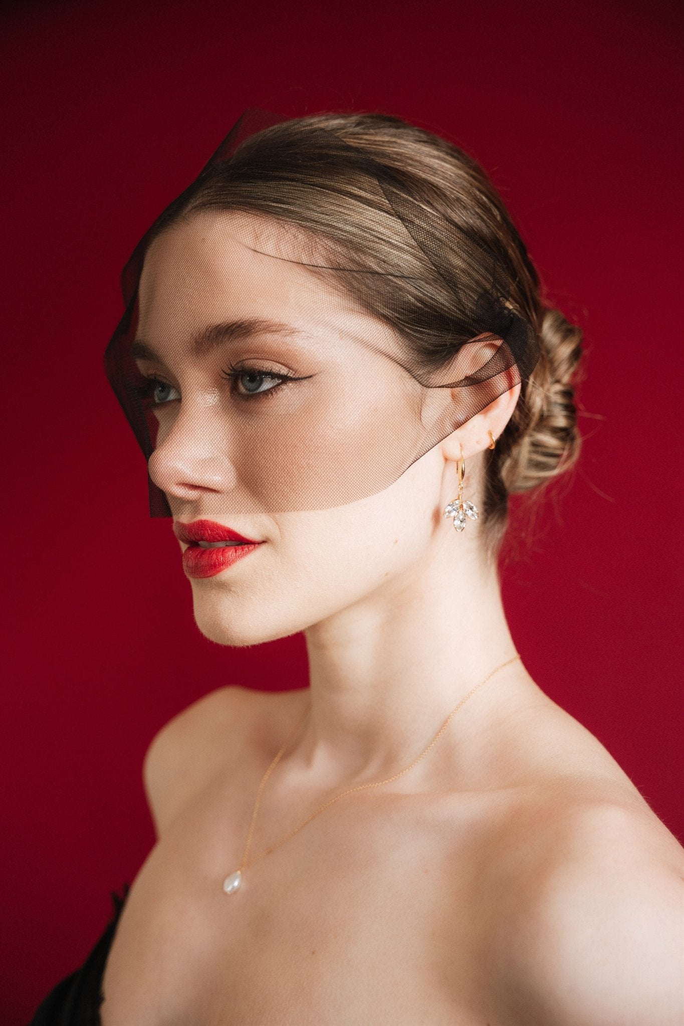 bride wears a gold baroque coin vegan pearl necklace, gold crystal drop earrings and a black tulle mask veil micro veil