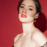 bride wears a gold baroque coin vegan pearl necklace, gold crystal drop earrings and a black tulle mask veil micro veil with black lace gown