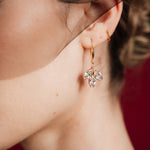 Close-up of a woman wearing gold crystal drop earrings