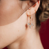 Close-up of a woman wearing gold crystal drop earrings