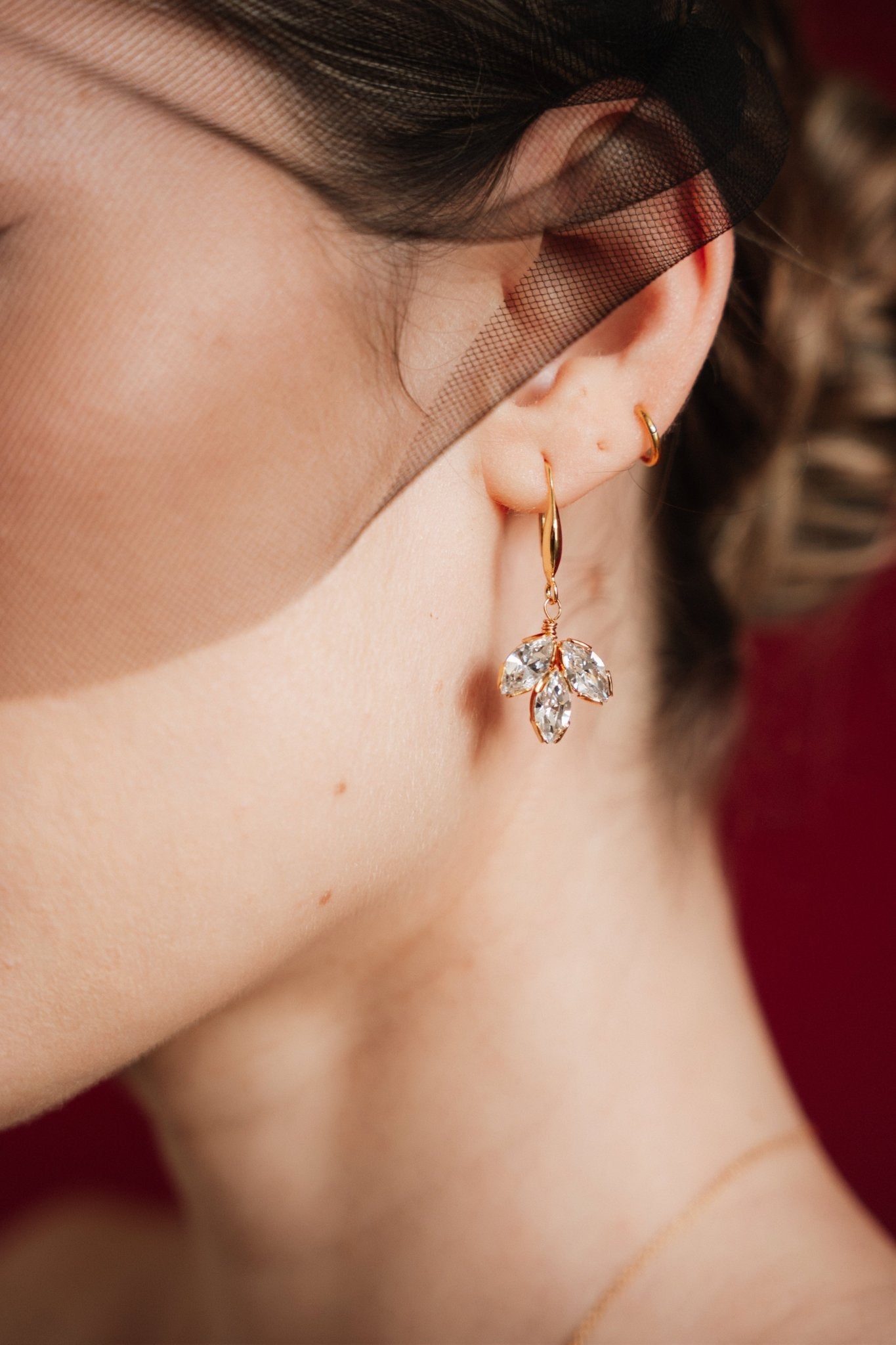 Close-up of a woman wearing gold crystal drop earrings