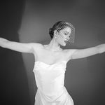 Woman wearing a white strapless dress and crystal birdcage veil black and white image