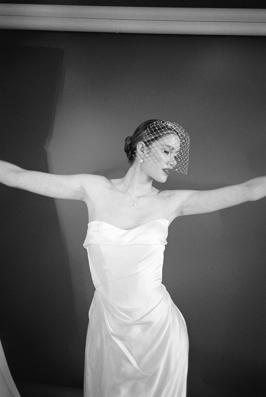 Woman wearing a white strapless dress and crystal birdcage veil black and white image