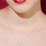 Woman wearing a white strapless dress and crystal birdcage veil against a red background with a baroque pearl necklace and matching earrings