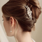 Woman with elegant hair styled in a bun with decorative pearl and crystal comb headpiece against a neutral background
